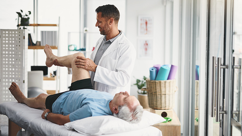 Shot of a young male physician assisting an older adult patient in recovery