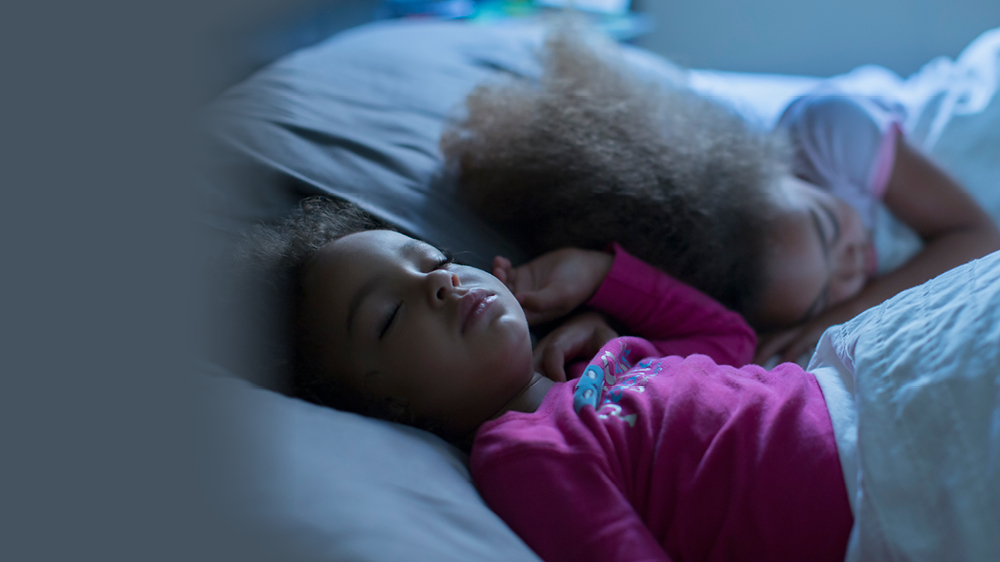 two young girls toddler aged sleeping in a shared bed